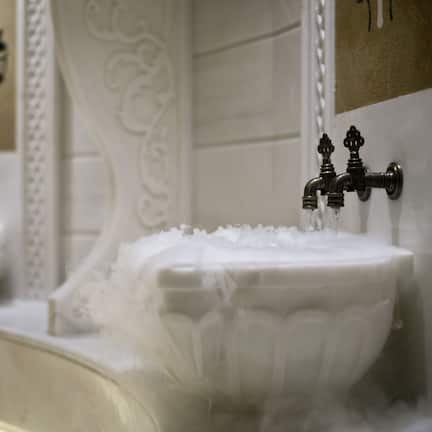 A bathroom with ornate white fixtures, including a sink and a bathtub with a decorative design.