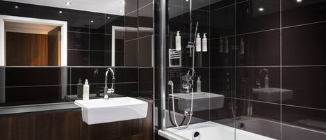 A modern bathroom with a glass-enclosed shower, a white sink, and dark wood cabinetry.