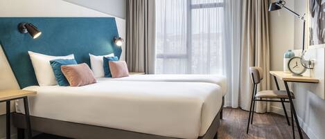 A modern hotel room with a large bed, a desk, and a chair.