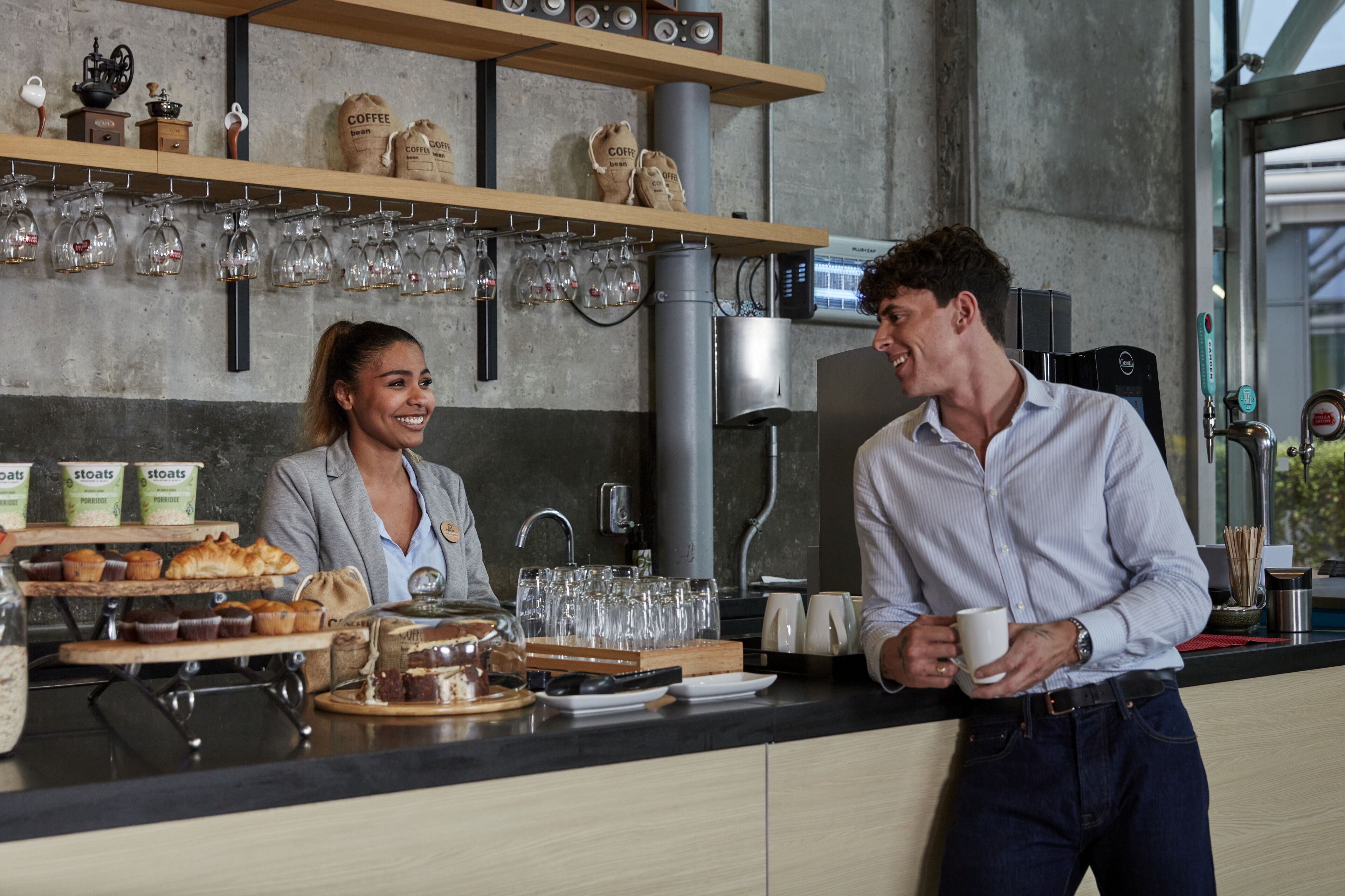 A coffee shop counter with pastries, coffee beans, and a coffee machine.