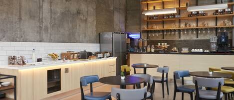 Una cuina moderna amb una illa central, zona de bar amb prestatges i places per a vuit persones.
