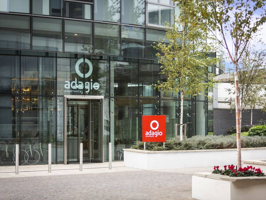 A modern building with a glass facade and a sign for 'adagio apartments'.