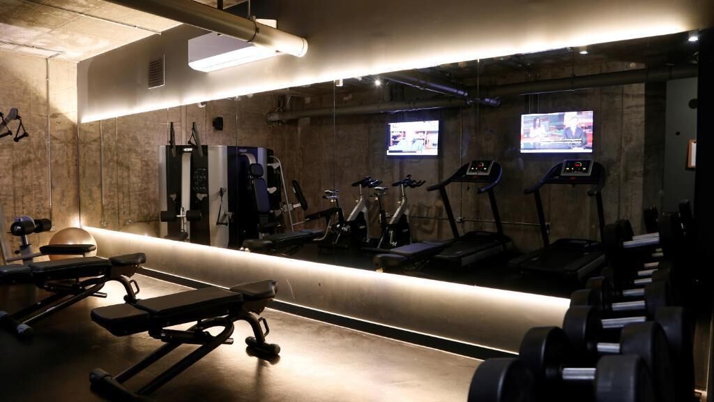 Un gimnasio con cintas de correr, elípticas y bancos de pesas.