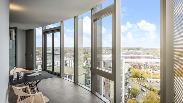 Een ruim balkon met grote ramen en uitzicht over de stad.