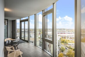 Un balcon spacieux doté de grandes fenêtres donnant sur la ville.