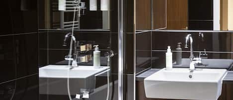 A modern bathroom with a glass-enclosed shower, a white sink, and a wooden vanity.