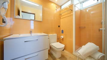 A modern bathroom with a white vanity, a toilet, a shower area, and a towel rack.