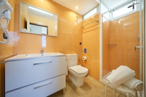 Uma casa de banho moderna com uma toucador branca, sanita, zona de duche e um porta-toalhas.