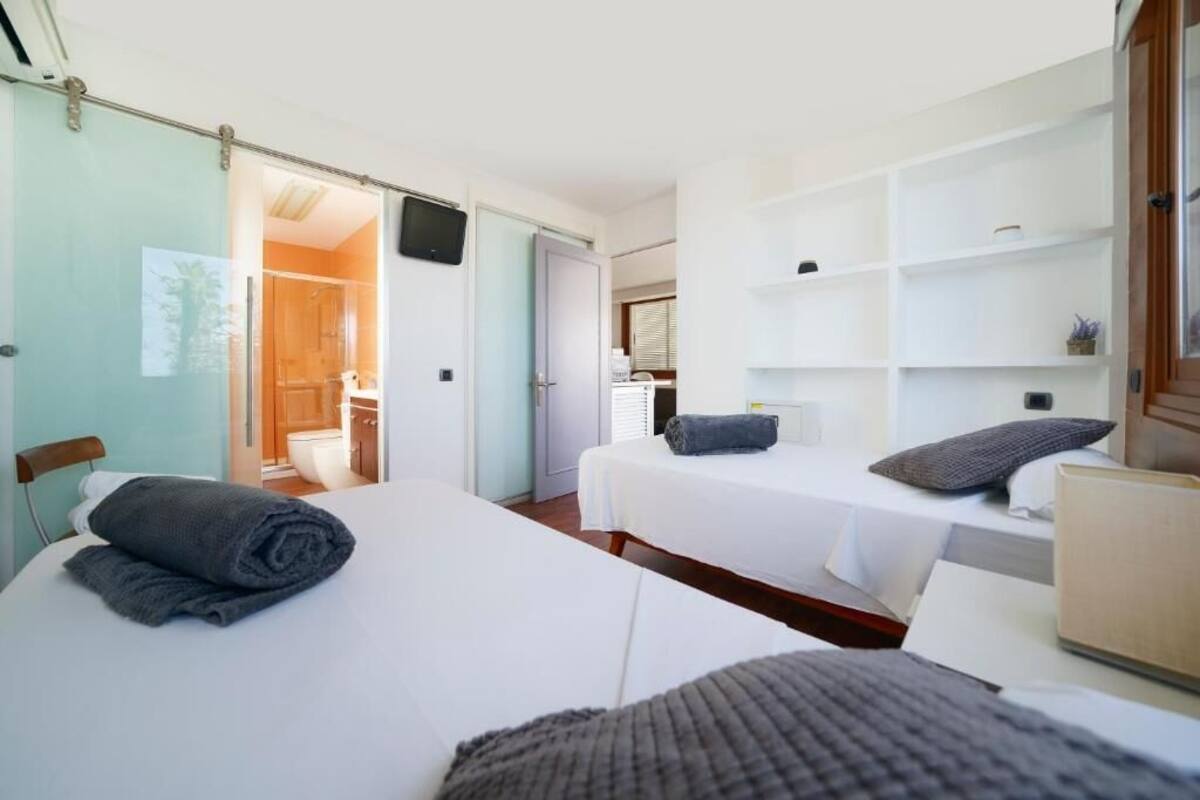 A hotel room with two beds, a small desk, and a bathroom visible through an open door.