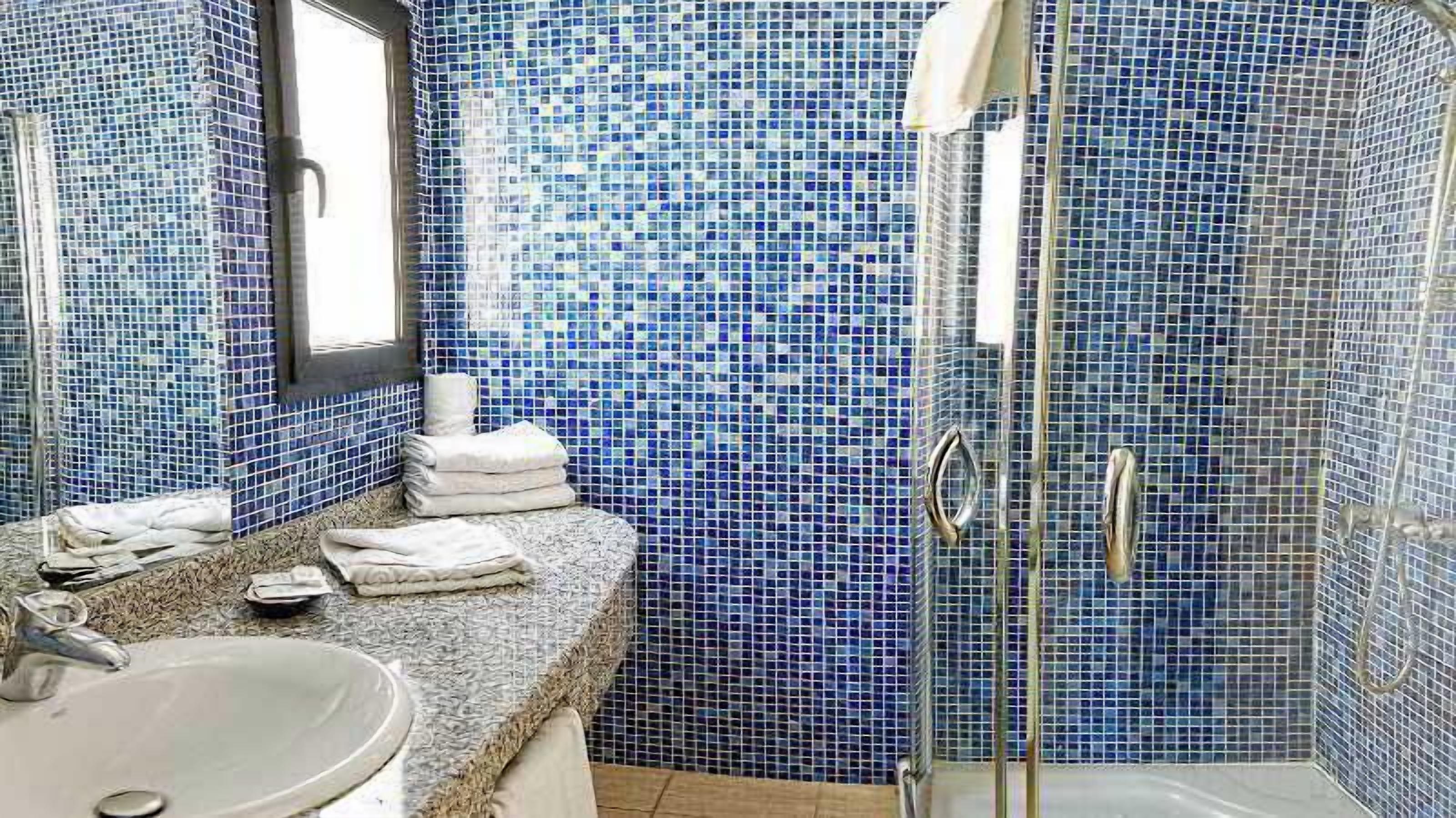 A bathroom with a sink, mirror, and glass shower enclosure.