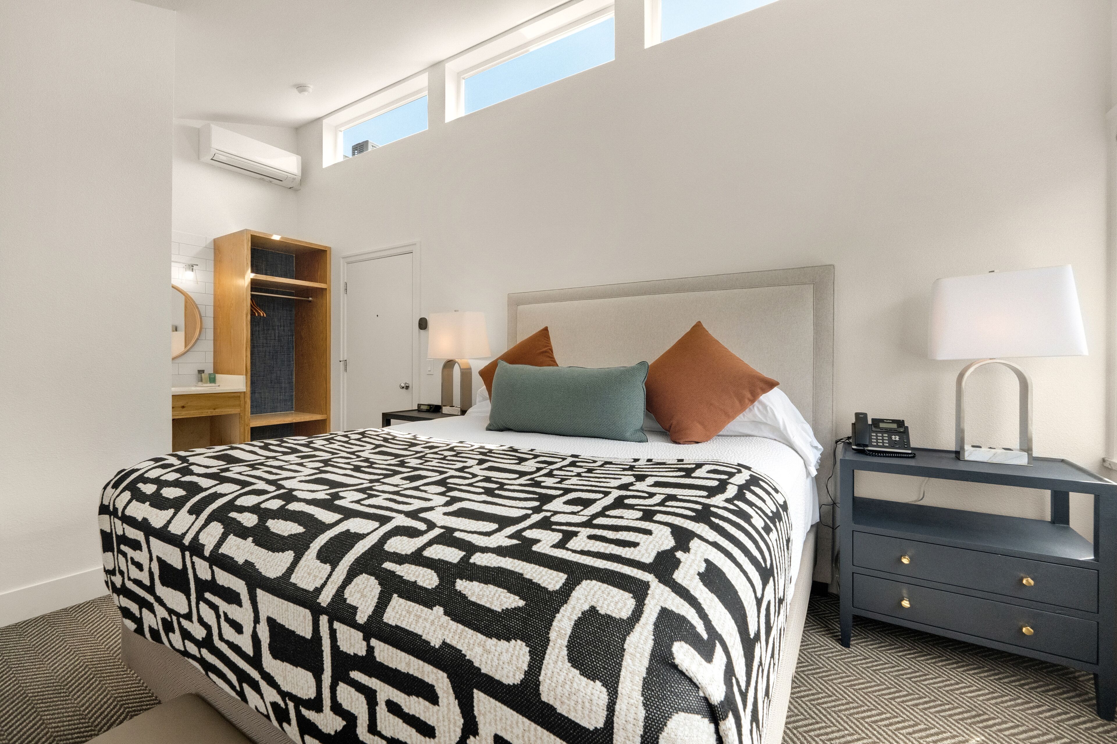 A hotel room with a large bed, a nightstand, a wardrobe, and a window with a view.