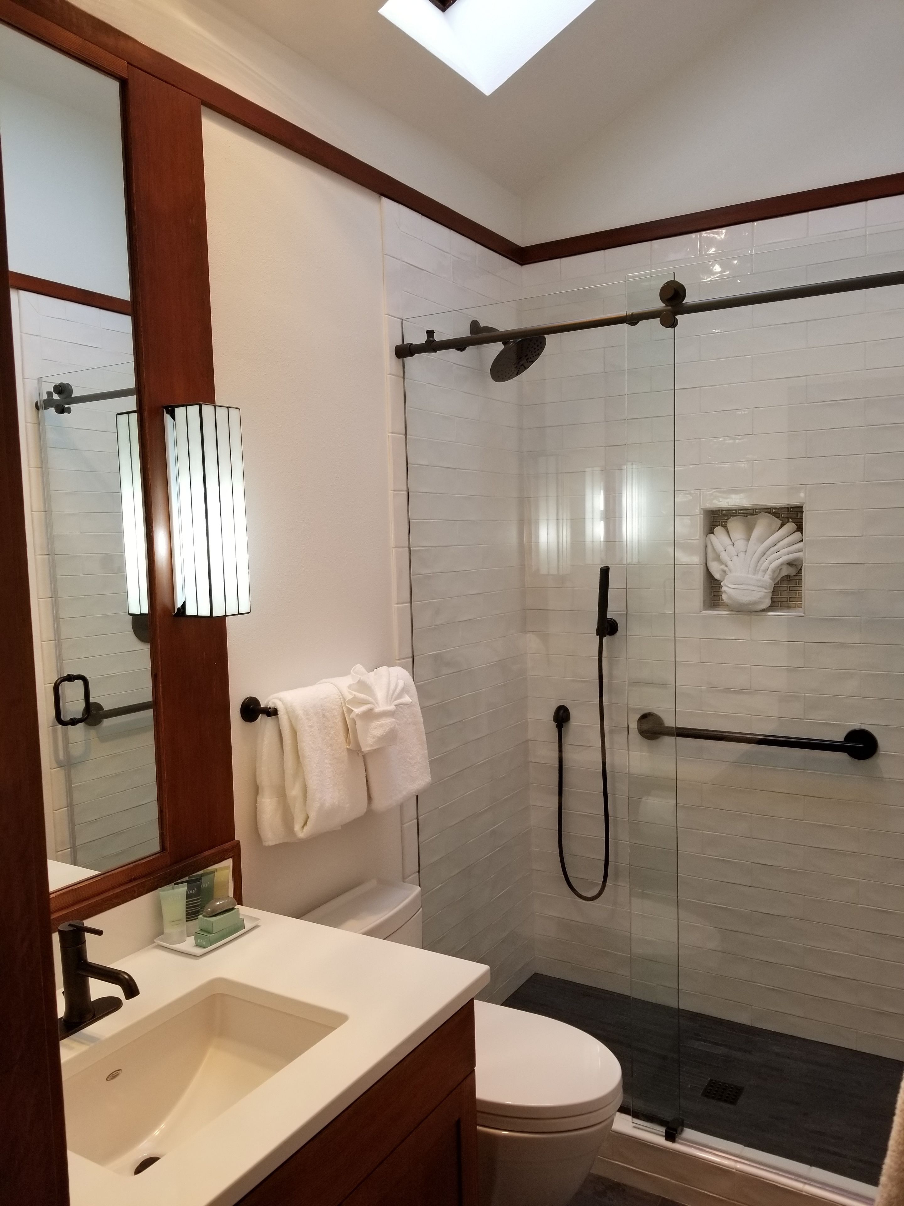 A modern bathroom with a glass-enclosed shower, a white sink, and a toilet.