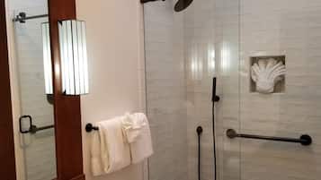 A modern bathroom with a glass-enclosed shower, a white sink, and a toilet.