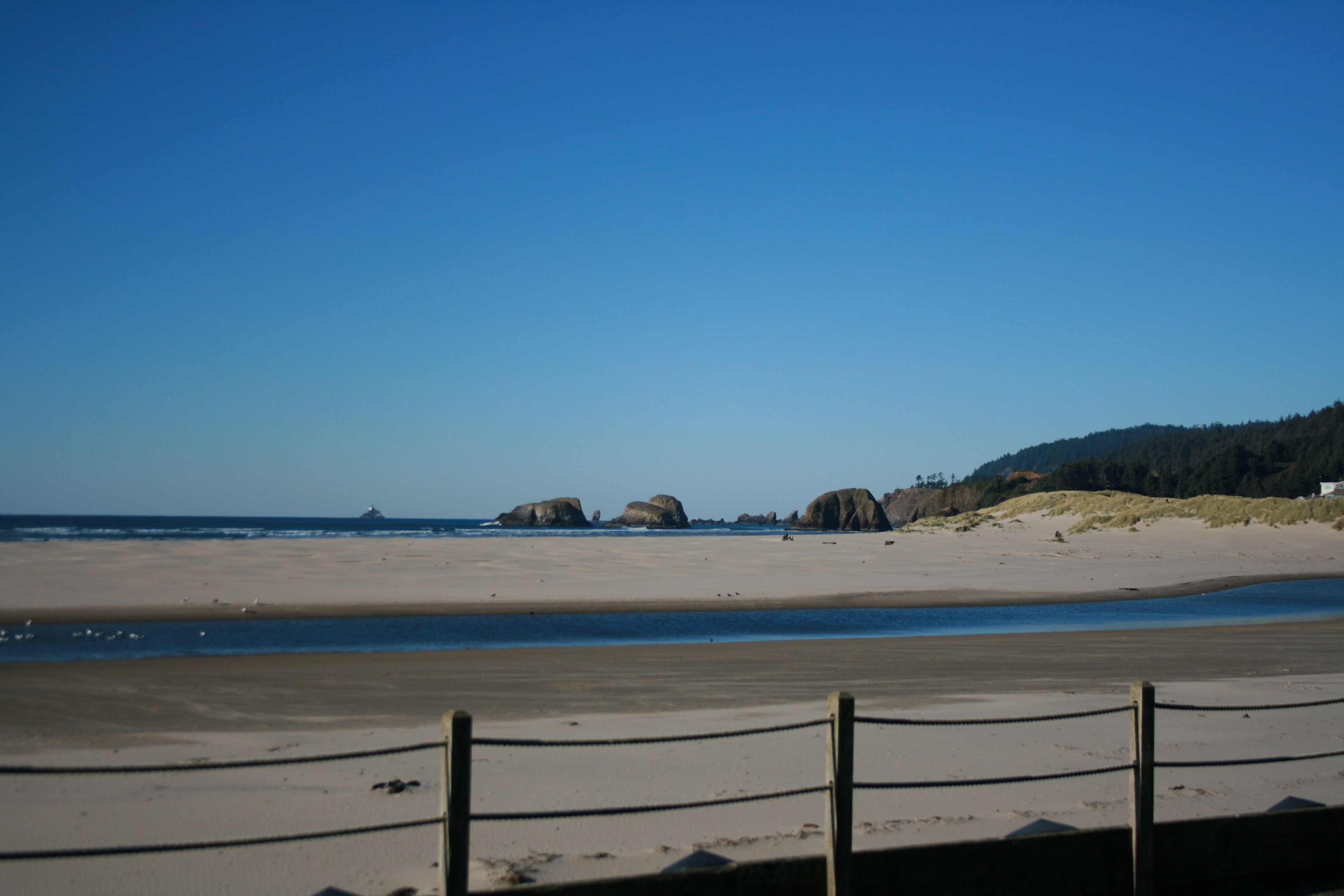A beach with a wooden fence and a clear sky.