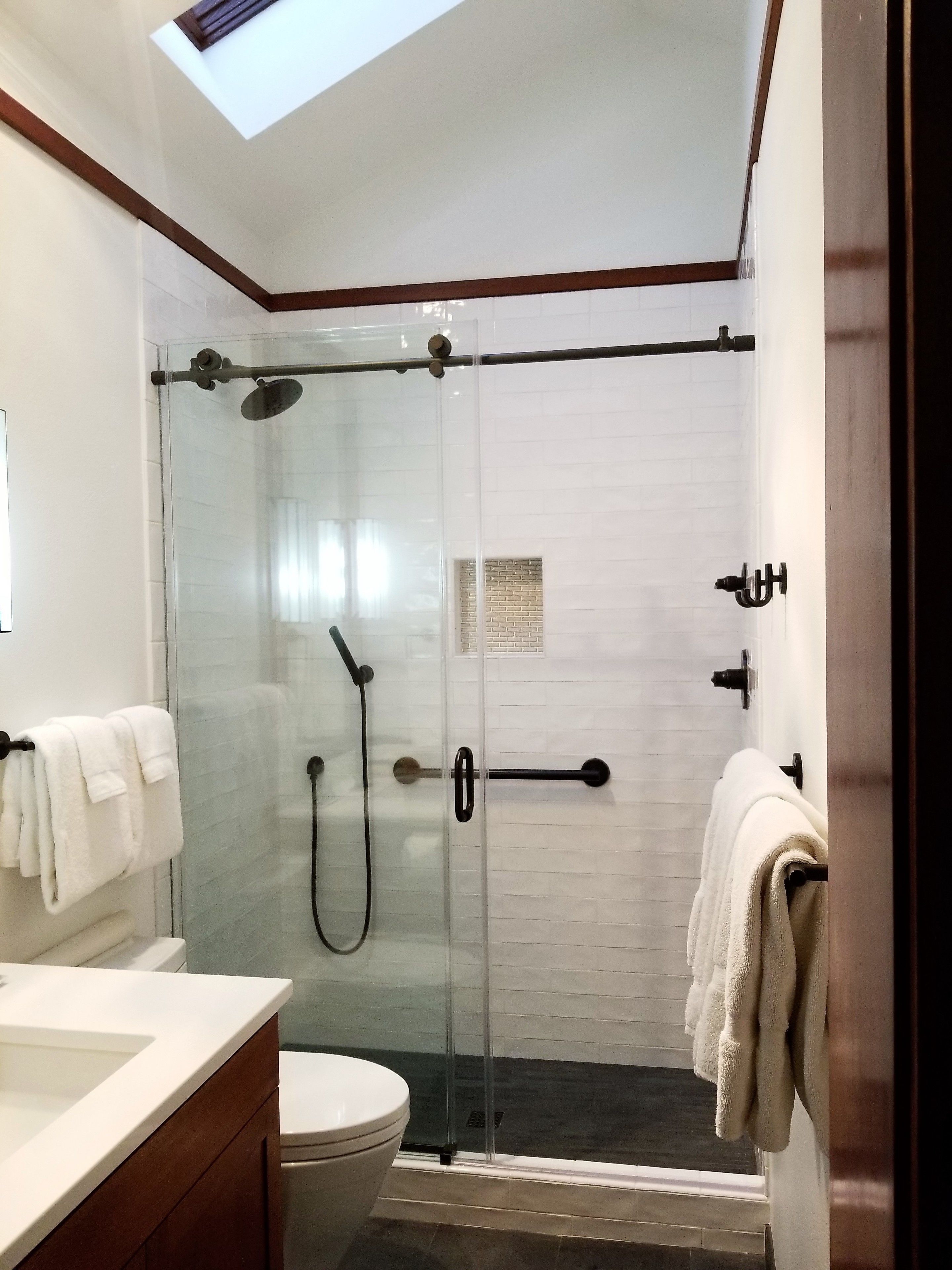 Un baño moderno con ducha de vidrio, inodoro y lavamanos.