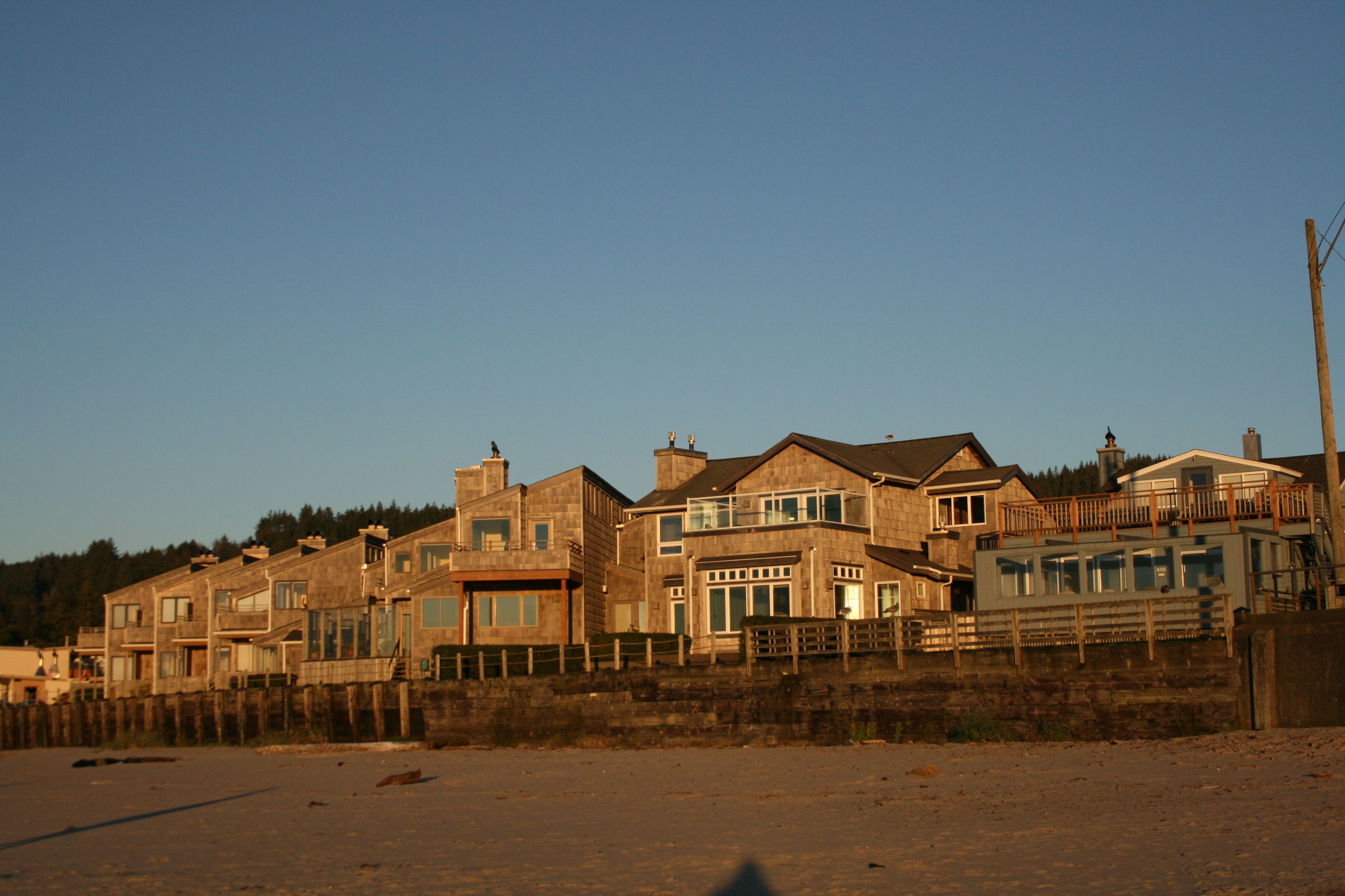 A coastal residential area with multiple two-story houses, a wooden fence, and a clear sky.
