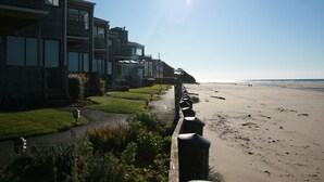 A beachfront property with modern architecture, a pathway leading to the beach, and a clear view of the ocean.