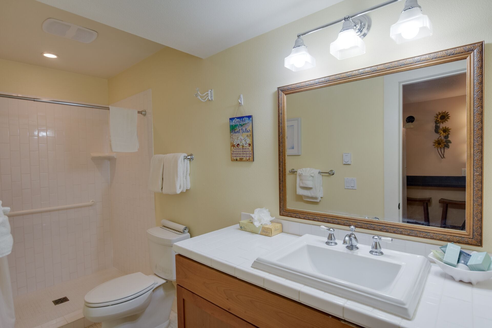 A bathroom with a shower, toilet, sink, and a large mirror.