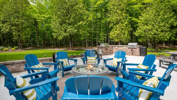 An outdoor seating area with blue Adirondack chairs and a central fire pit. - Somerset Inn & Suites (Ephraim)