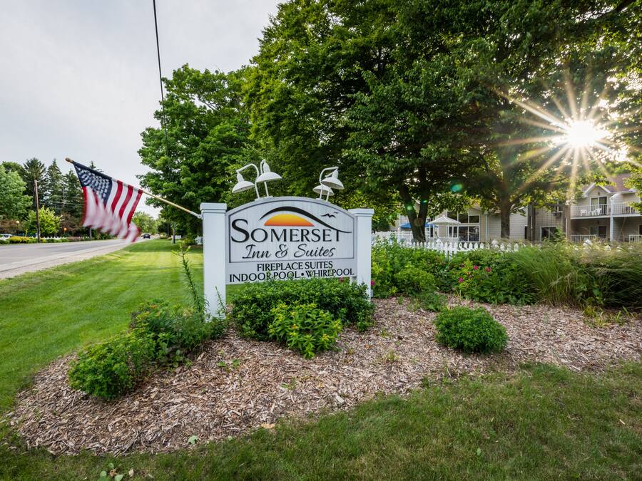 Señal de Somerset Inn & Suites con una bandera, árboles y una valla de fondo.
