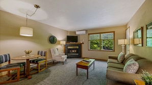 A living room with a fireplace, a dining table with chairs, a sofa, and a coffee table. - Somerset Inn & Suites (Ephraim)