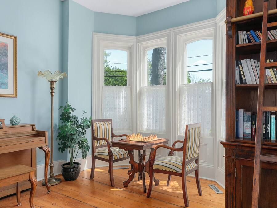 Una habitación con un piano de madera, un tablero de ajedrez y una estantería.