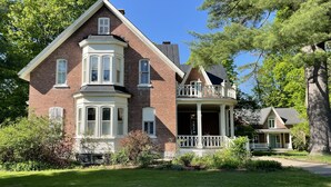 A large brick house with a bay window, a balcony, and a covered porch. - Manoir Sweetsburg (Cowansville)