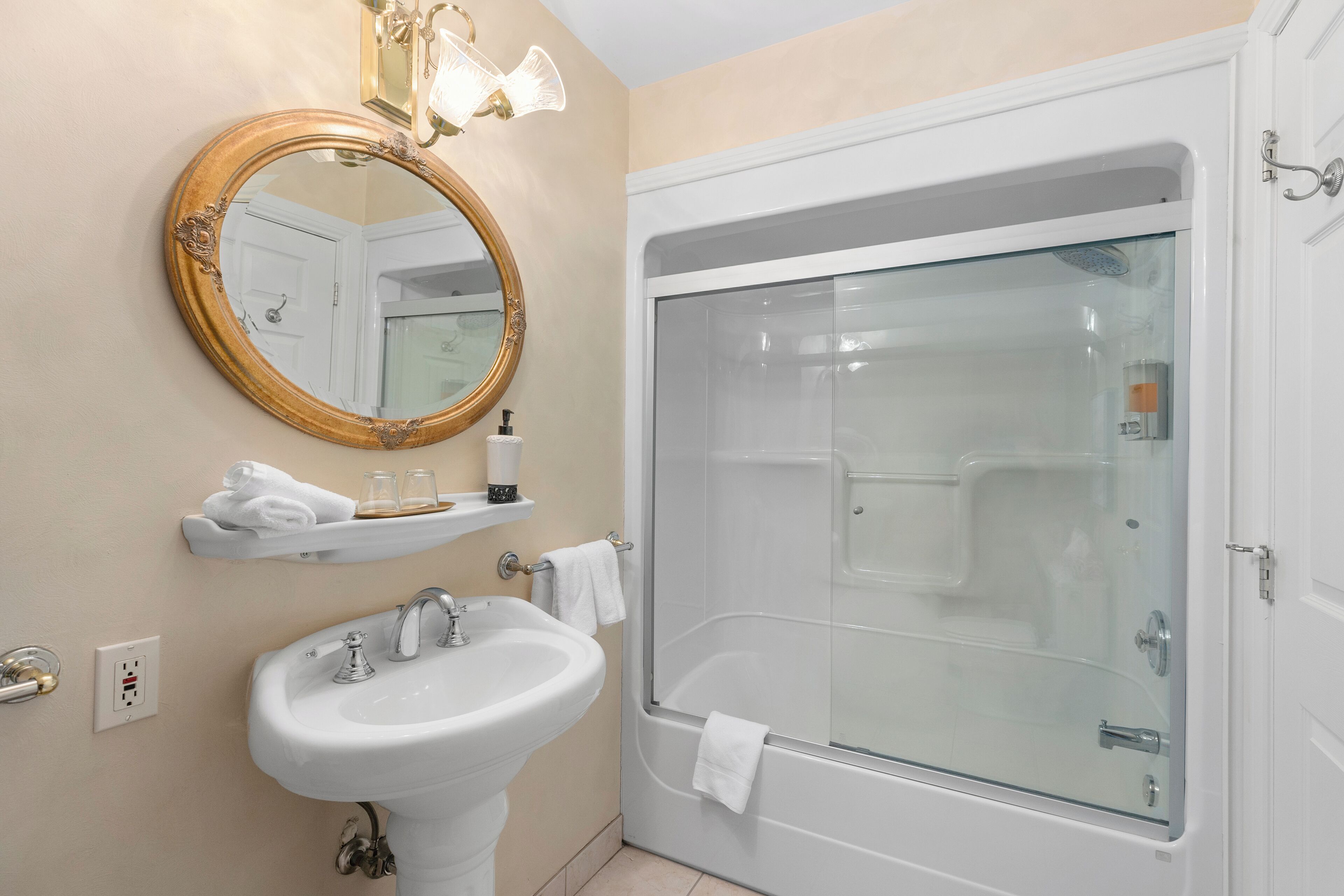 Un baño con lavabo, espejo y bañera con mampara de vidrio.