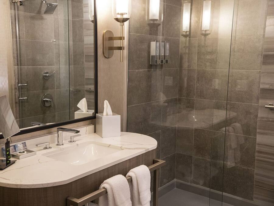 A modern bathroom with a glass shower enclosure, a vanity with a mirror, and a towel rack.