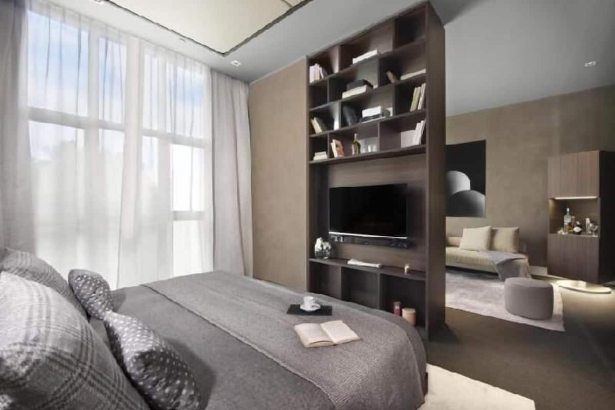 A modern bedroom with a large bed, a TV, and a bookshelf.