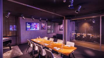 Un salón de conferencias con una larga mesa de madera, sillas blancas y un separador de vidrio con la marca 'STK'.