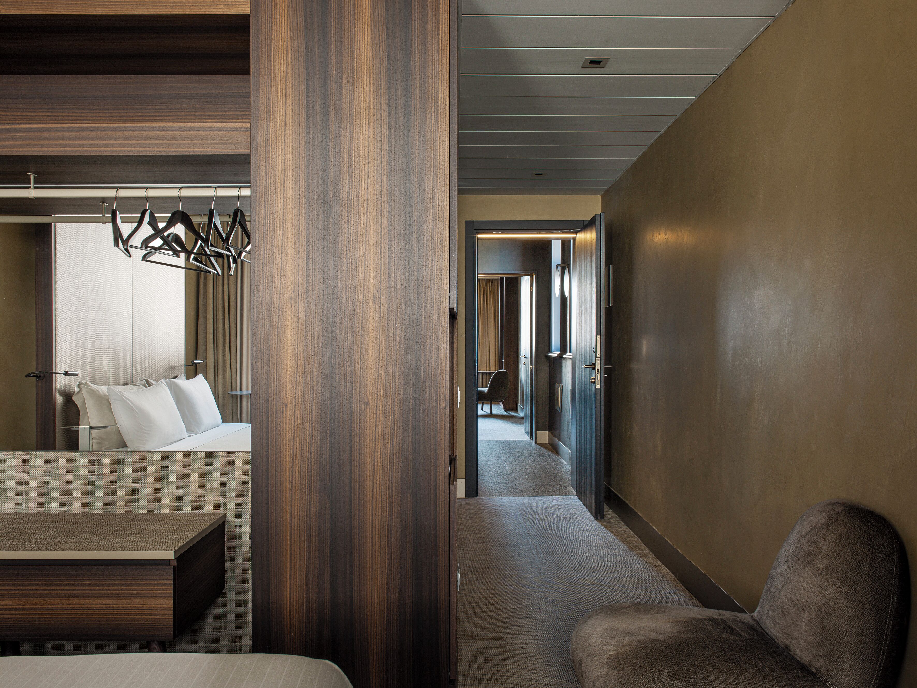 Habitación de hotel moderna con cama, zona de estar y pasillo que conduce a otra habitación.