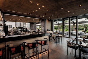 A modern bar area with a high ceiling, large windows, and a view of the cityscape. - ME Milan - Il Duca (Milan)