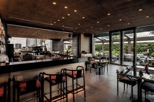 Un'area bar moderna con soffitto alto, ampie finestre e vista sulla città.