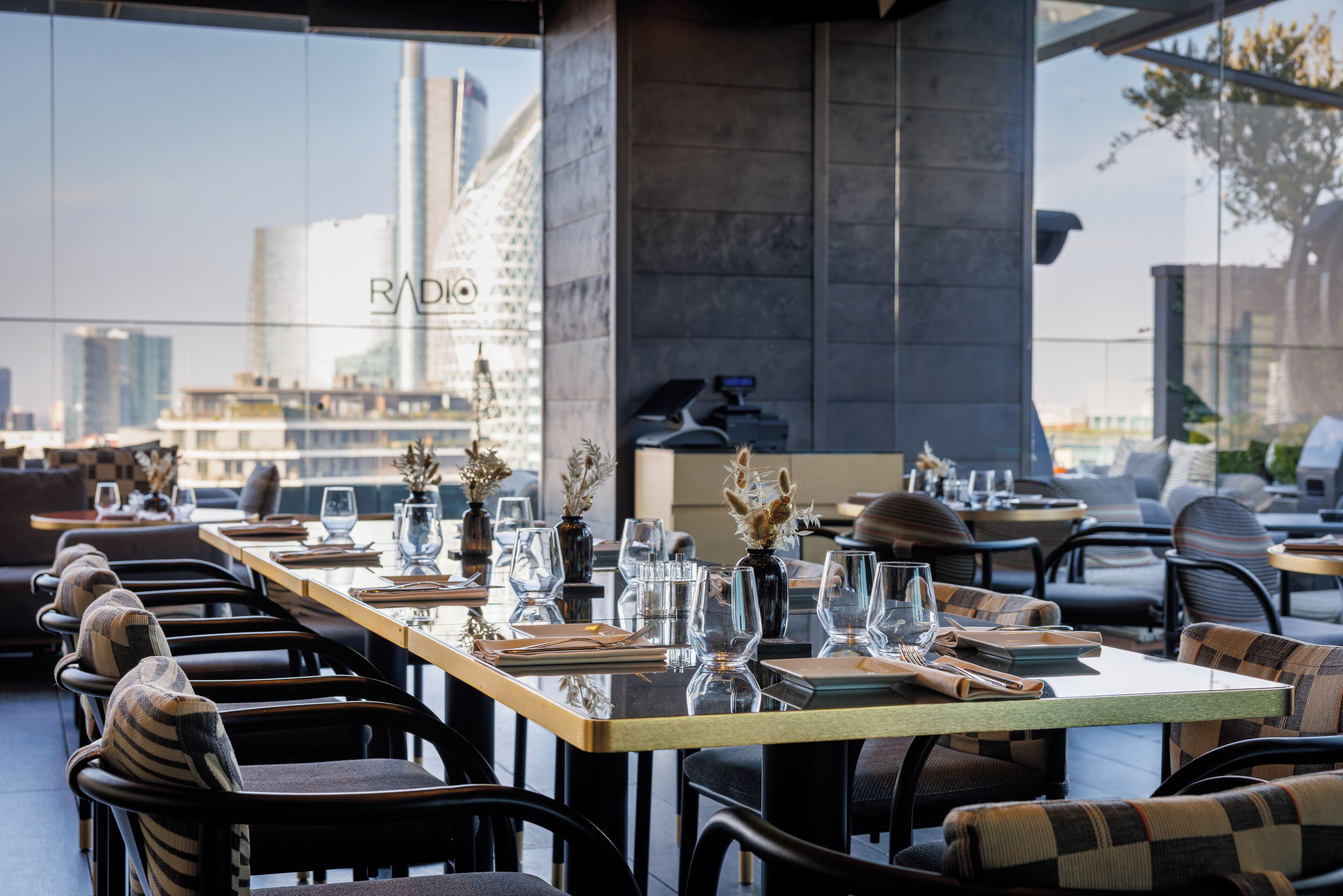 Un restaurante con mesas dispuestas para comer, sillas y vistas a la ciudad.