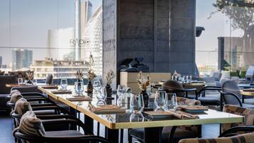 Un restaurante con mesas dispuestas para comer, sillas y vistas a la ciudad.