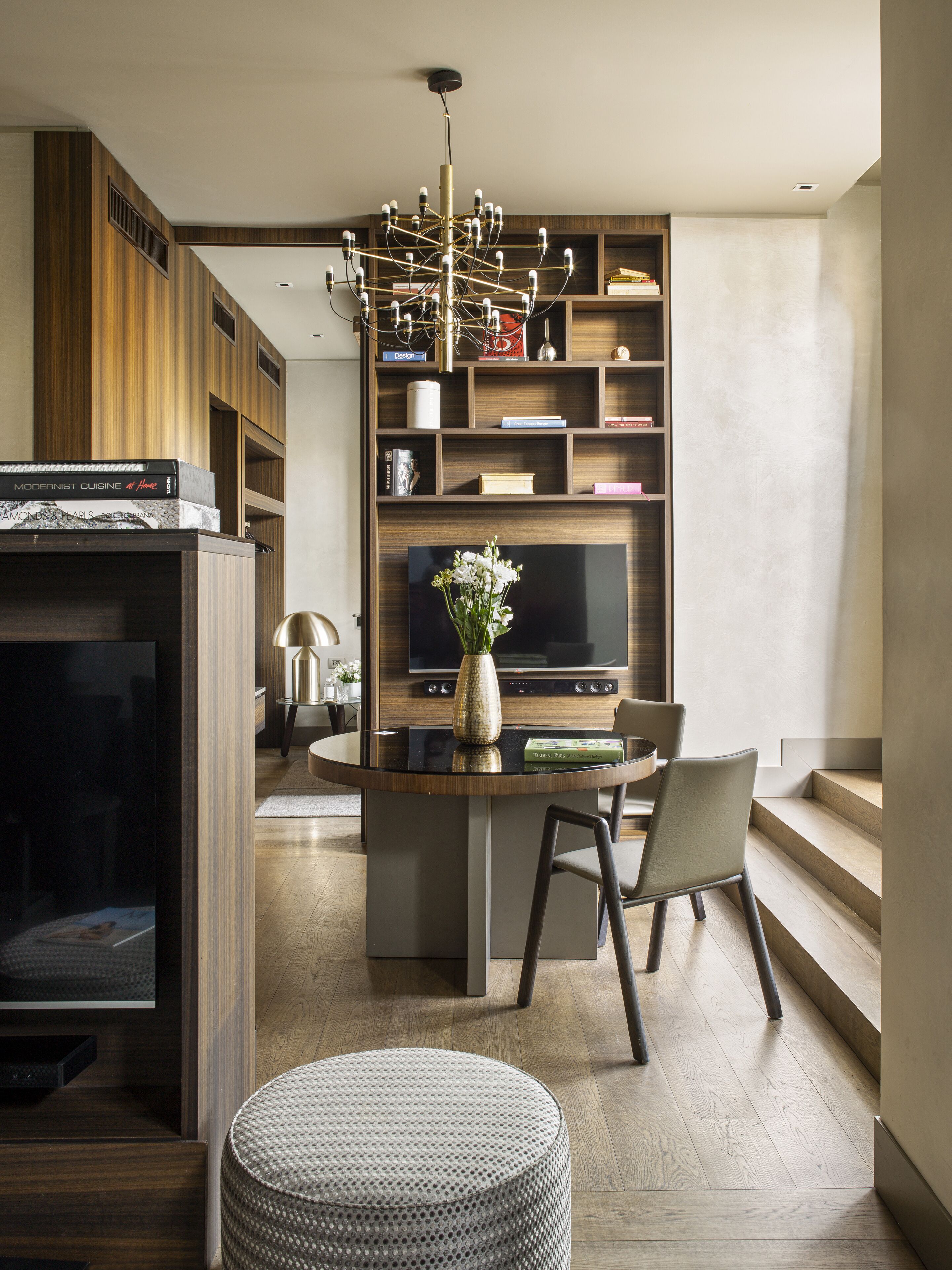 A modern living room with a central island, a television, and a bookshelf.