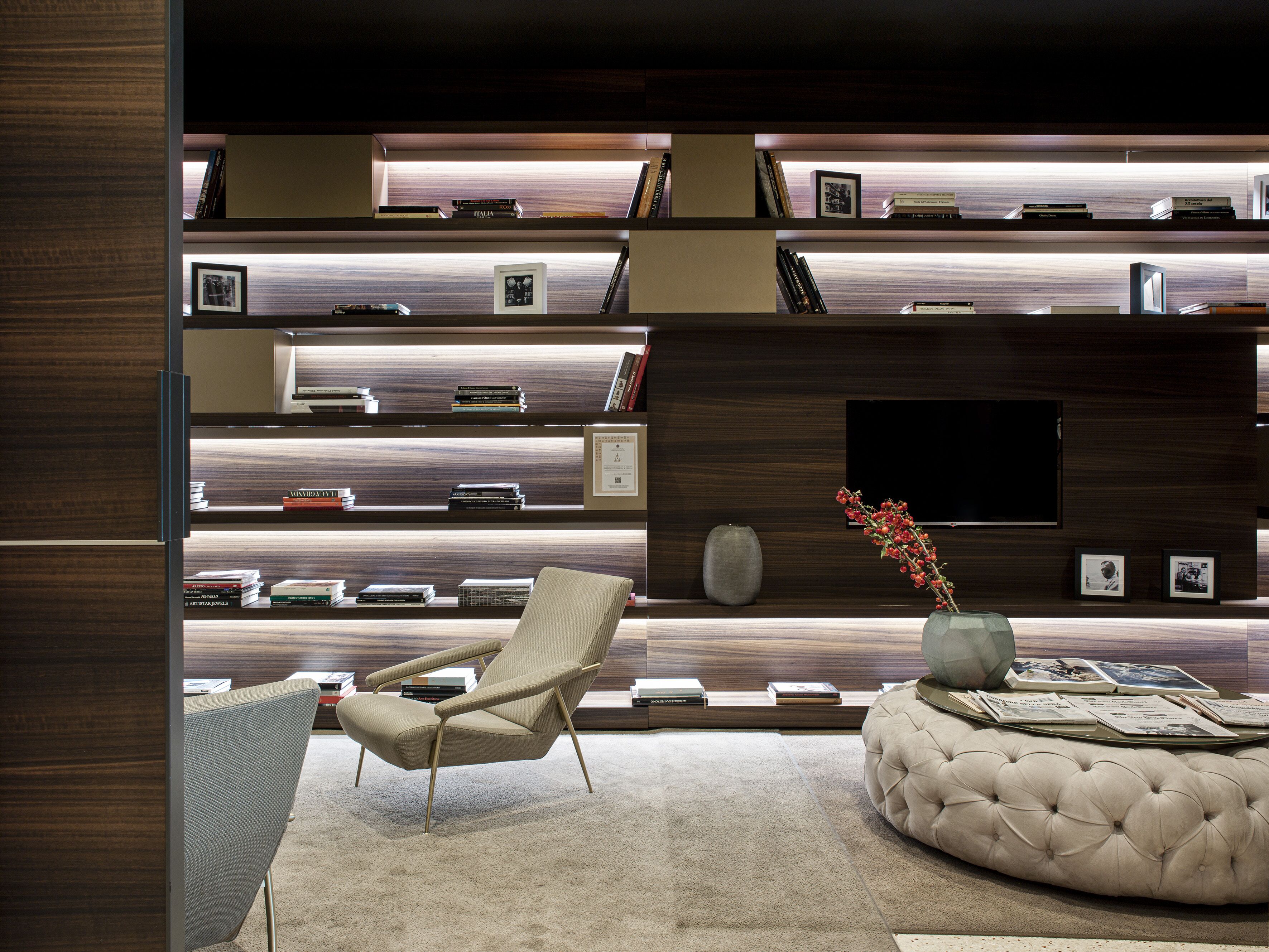 A modern living room with a sofa, a chair, a coffee table, and a bookshelf with books and framed pictures.