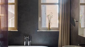 A modern bathroom with a freestanding bathtub, a large sink, and a window with curtains.