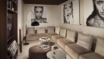 A modern living room with a sectional sofa, a round ottoman, a small coffee table, a floor lamp, and a bookshelf.