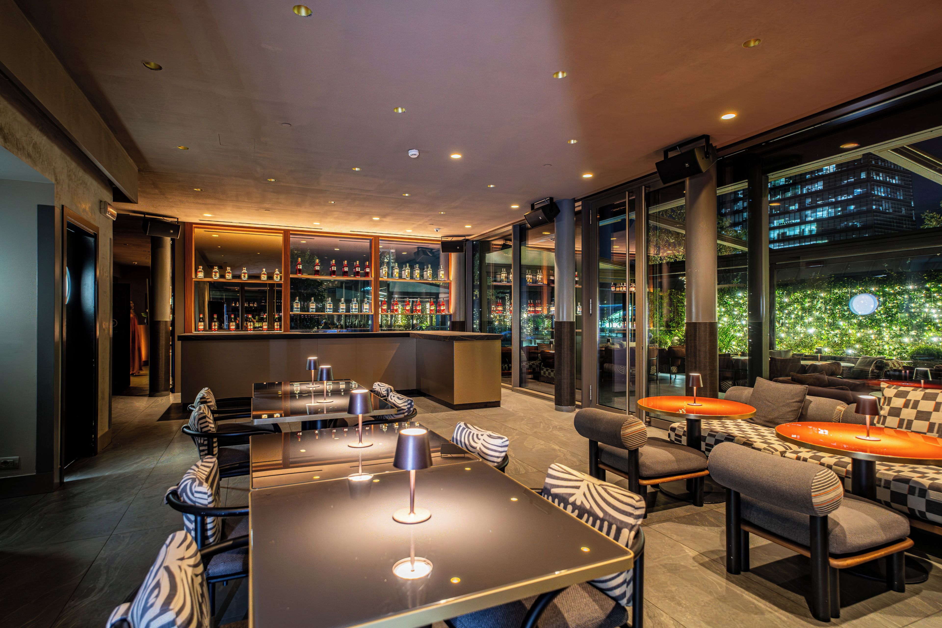 A modern bar area with seating and a view of a cityscape.