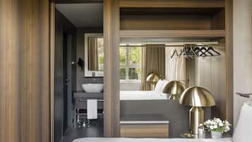 A modern hotel room with a large bed, a bathroom with a sink and mirror, and a view of the outdoors.