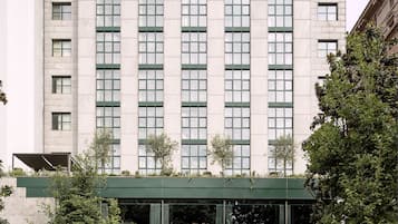 A multi-story hotel with a brick facade, large windows, and a covered entrance with greenery.