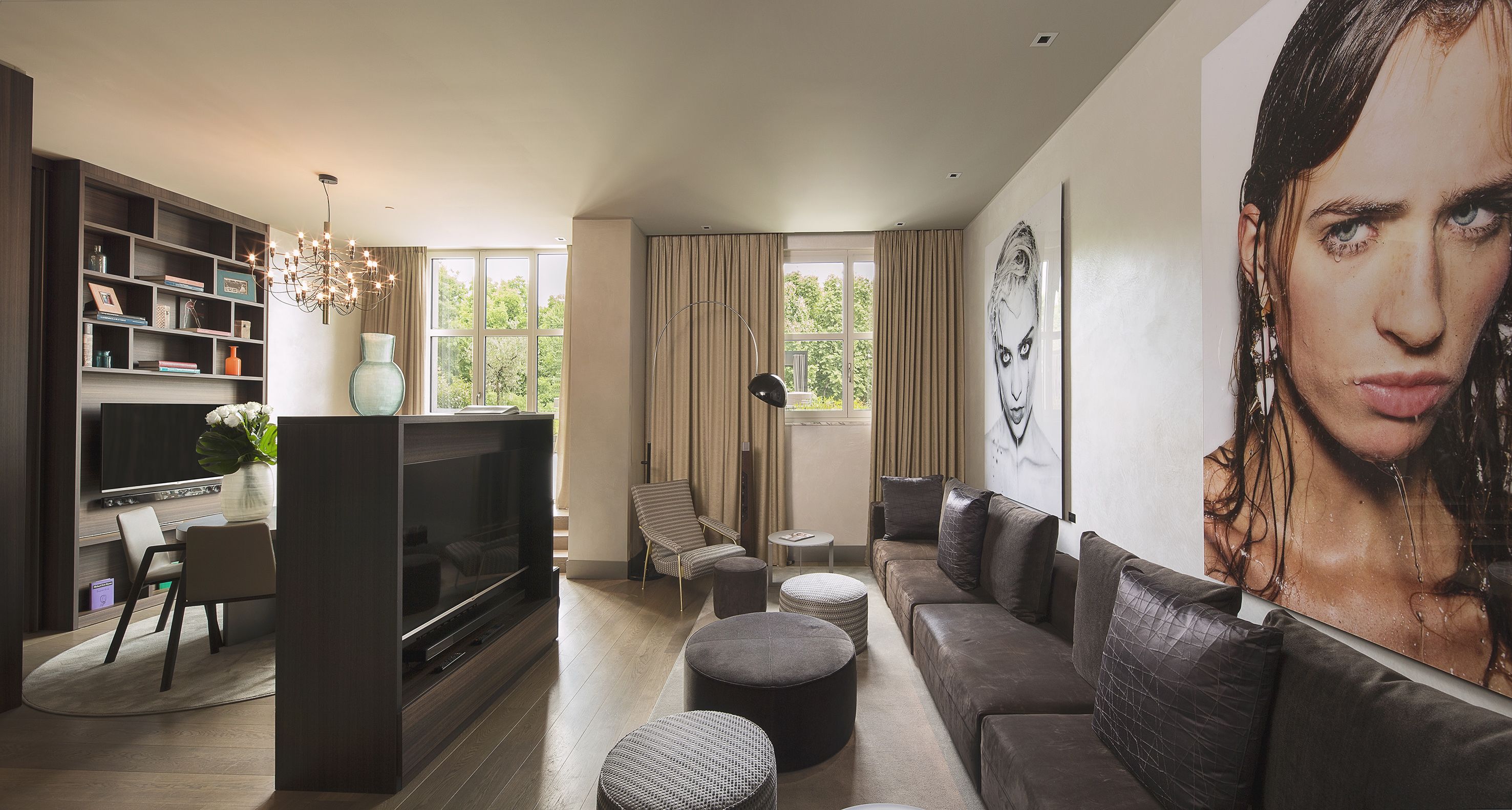 A modern living room with a flat-screen TV, a bookshelf, a sofa, and a large painting.