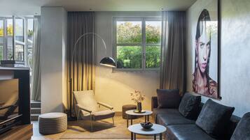 Una sala de estar moderna con un sofá, una silla, una mesa de centro, una lámpara de pie y un ventanal con cortinas.