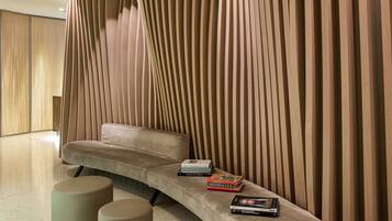 Ein modernes Interieur mit einer gebogenen Couch, einem kleinen Tisch mit Büchern und einer Wand mit vertikalen Holzlatten.