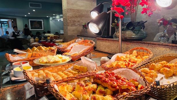 A buffet with various food items in baskets, including bread, pastries, and desserts. - Hotel Princesa Louçã (Belém)