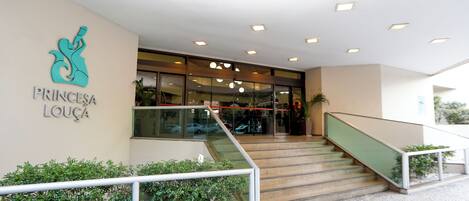 A modern building entrance with a staircase, a glass door, and a sign reading "PRINCESA LOUÇA".
