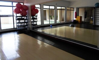Uma academia com espelho na parede, equipamentos de exercícios e uma janela grande.