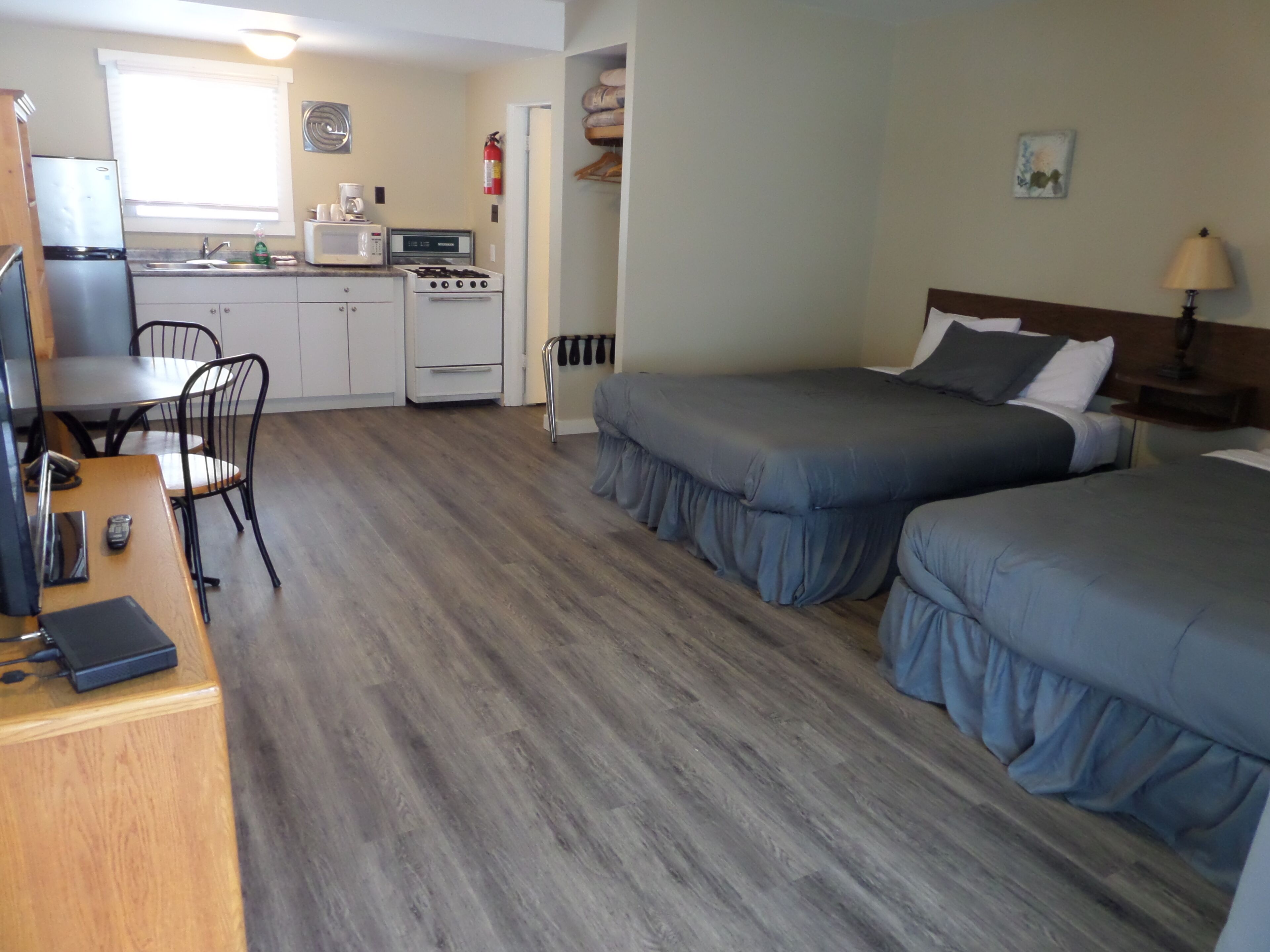 Une chambre compacte comprenant un coin cuisine, deux lits, un bureau et une chaise.